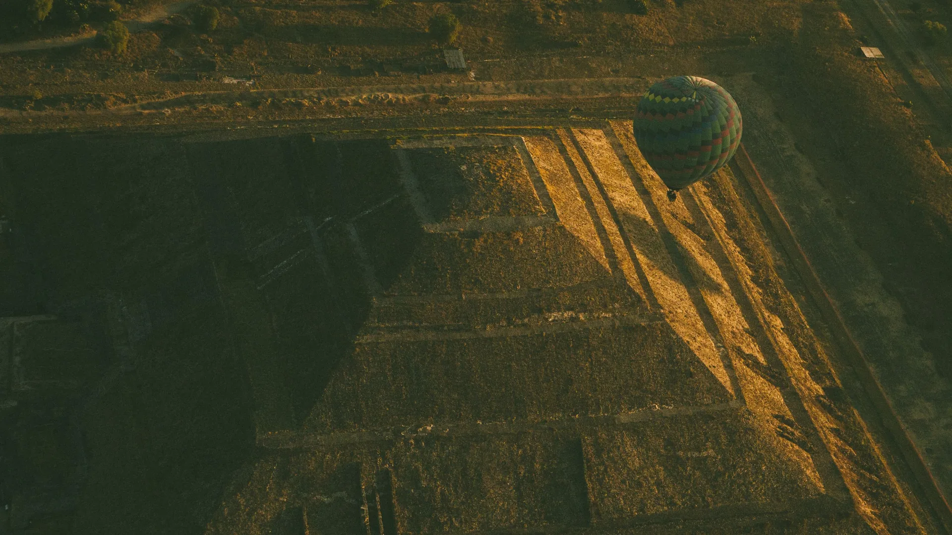 A hot-air balloon rising at sunrise above the pyramids of Teotihuacán